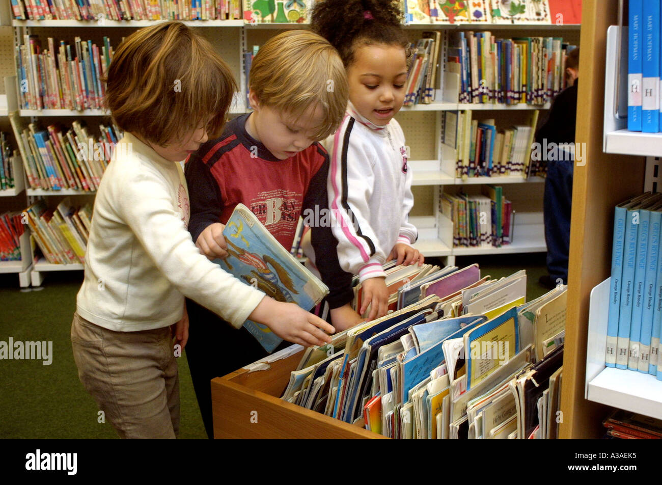 Bambini della scuola materna guardando i libri in biblioteca Foto Stock