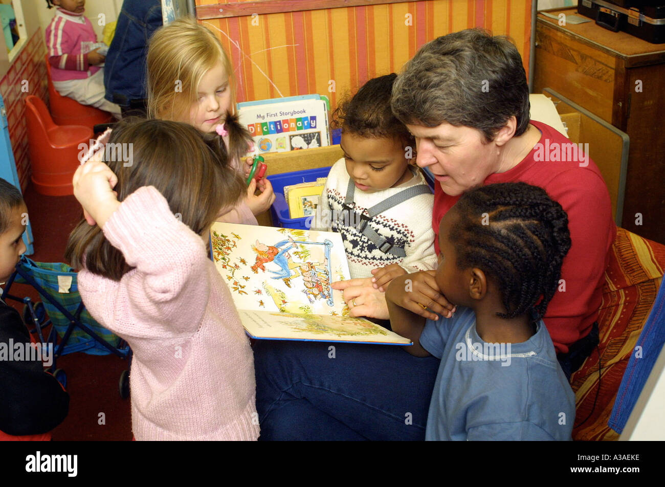 Scuola materna insegnante lettura per bambini in classe Foto Stock