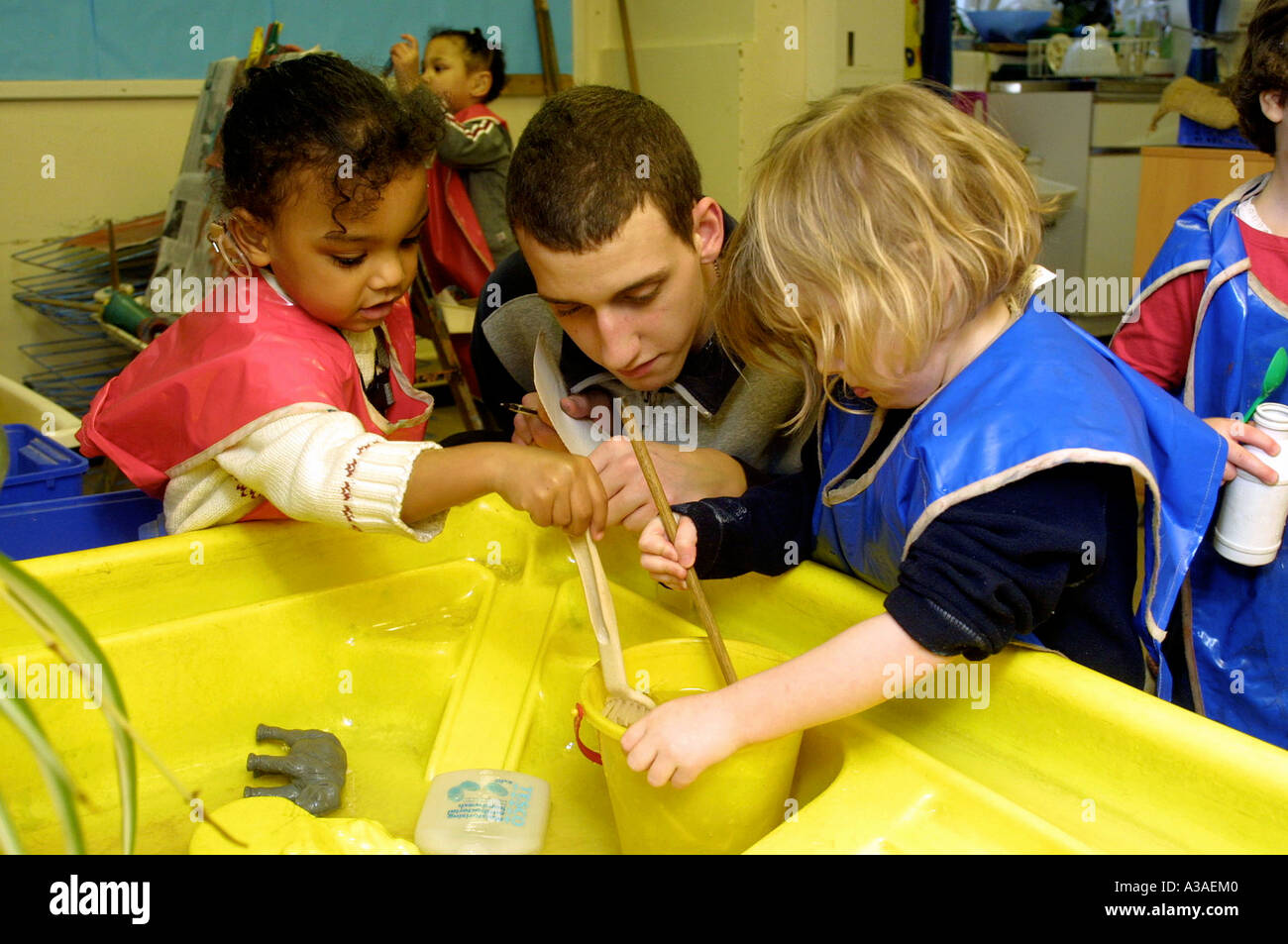 Vivaio maschio insegnante della scuola a giocare con i bambini in aula. Foto Stock