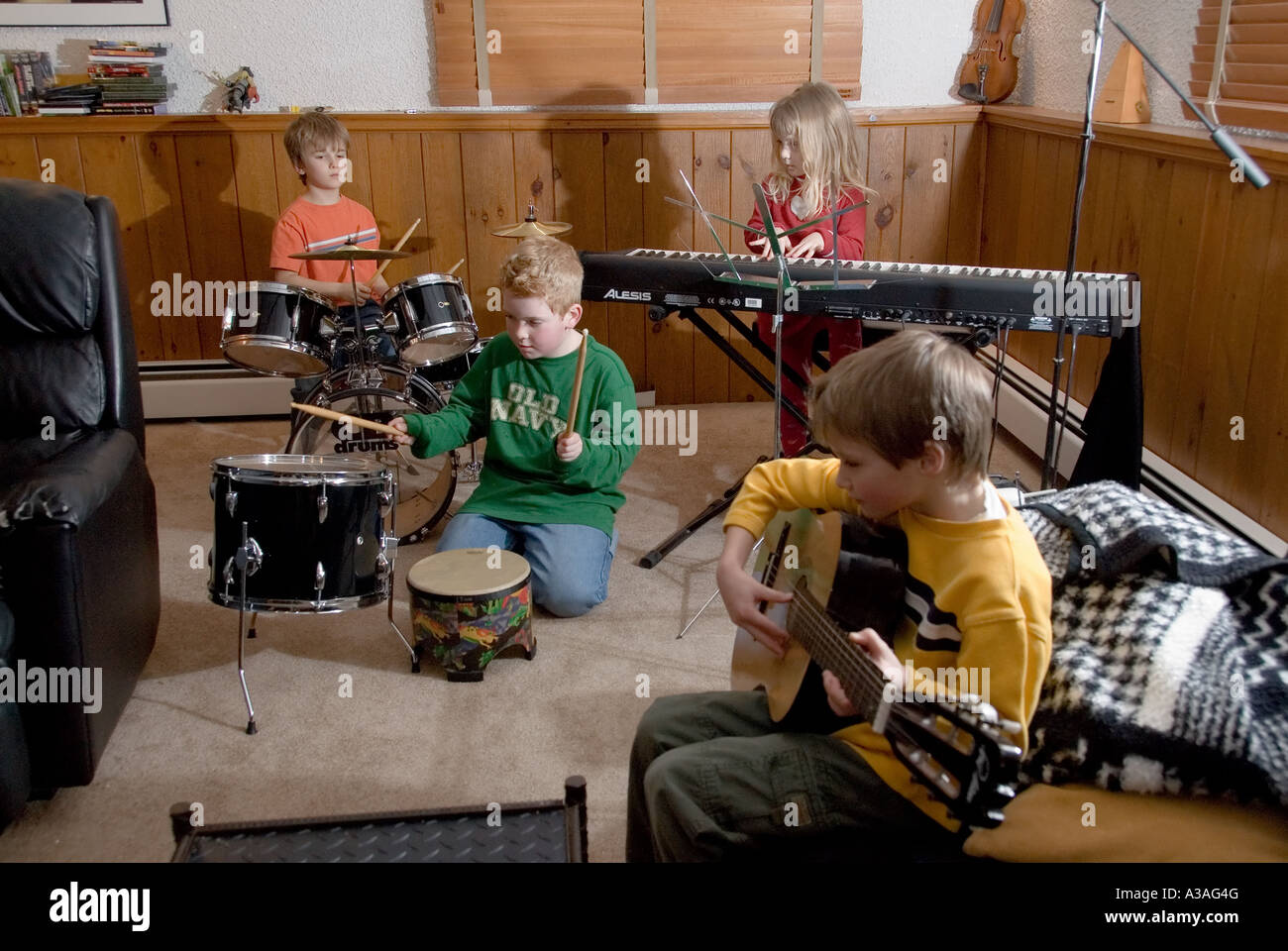 P33 036 Tre 7-Year-Old caucasian ragazzi e un 5 anno vecchia ragazza riproduzione di musica 2 - i tamburi tastiera gu Foto Stock