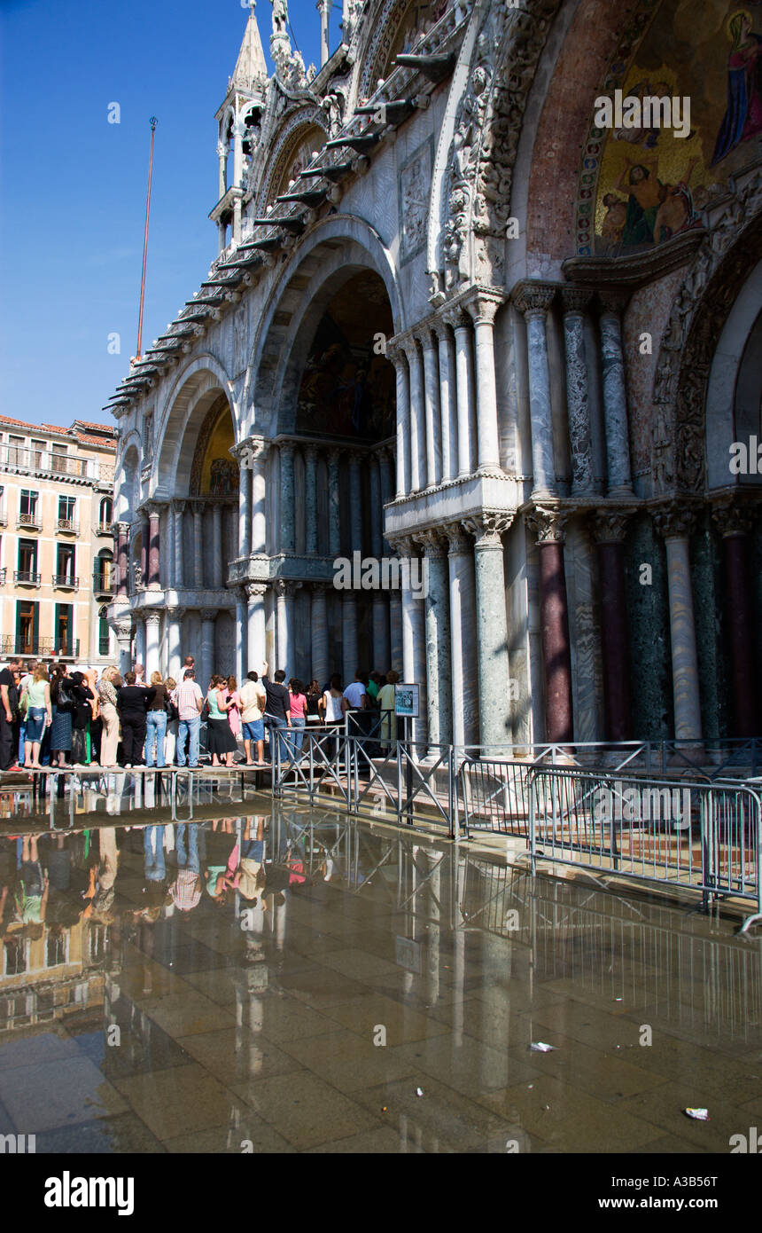 Italia Veneto Venezia Aqua Alta Alta allagamenti in Piazza San Marco. Turisti entrare la chiesa della basilica sulla passerella rialzata Foto Stock