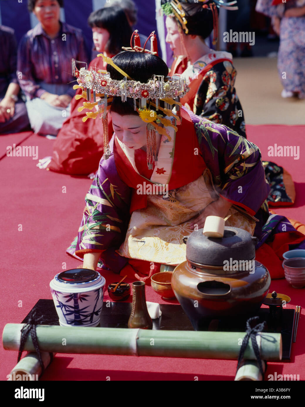 Giappone Honshu Kyoto donna in costume di Corte kimono e copricapo preparando la tradizionale cerimonia del tè Foto Stock