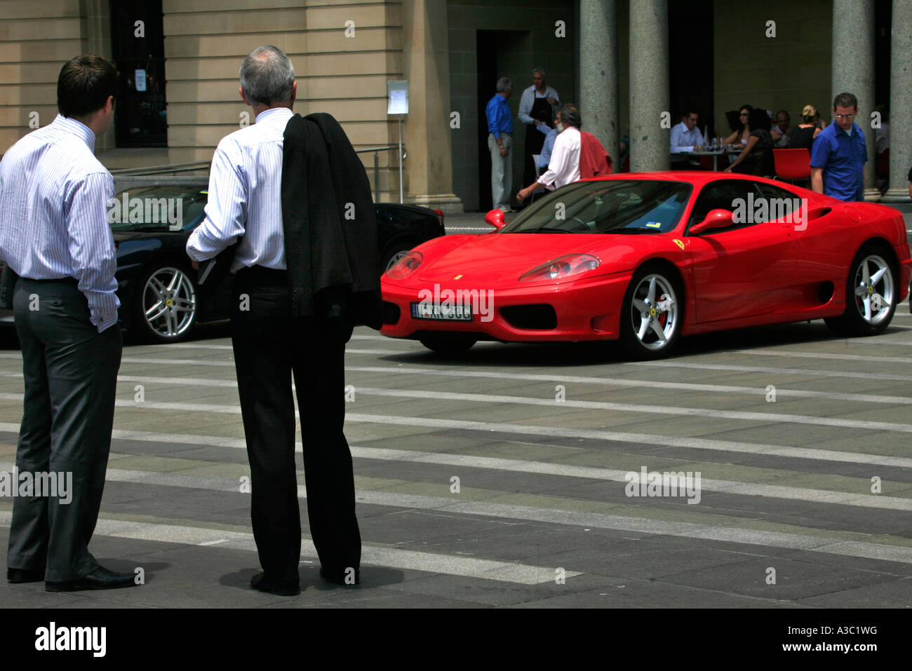 Imprenditori e passanti ispezionare un rosso Ferrari sul display esterno il Customs House di Sydney in Australia Foto Stock