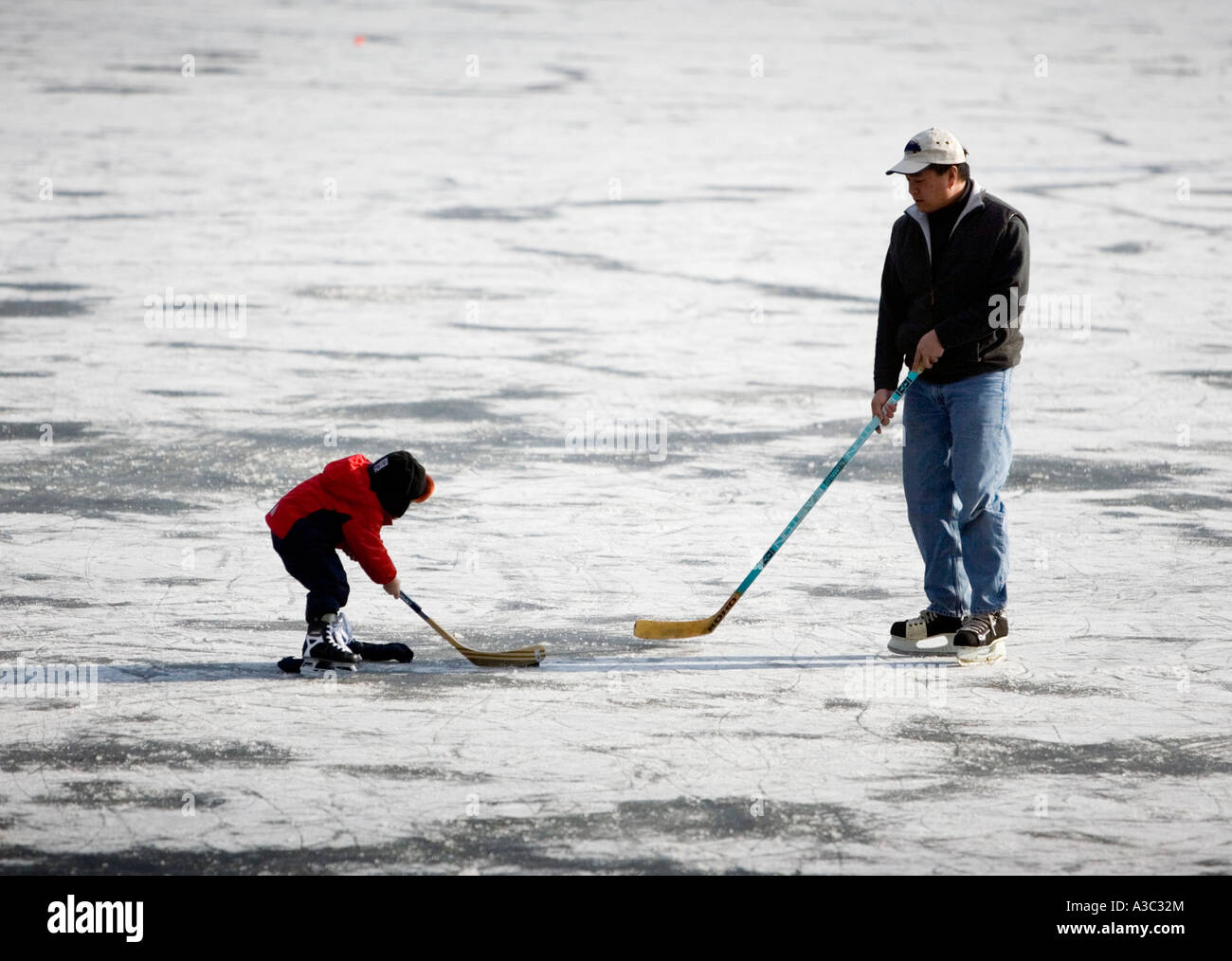 Padre e figlio giocano a hockey su ghiaccio su un lago ghiacciato Foto Stock