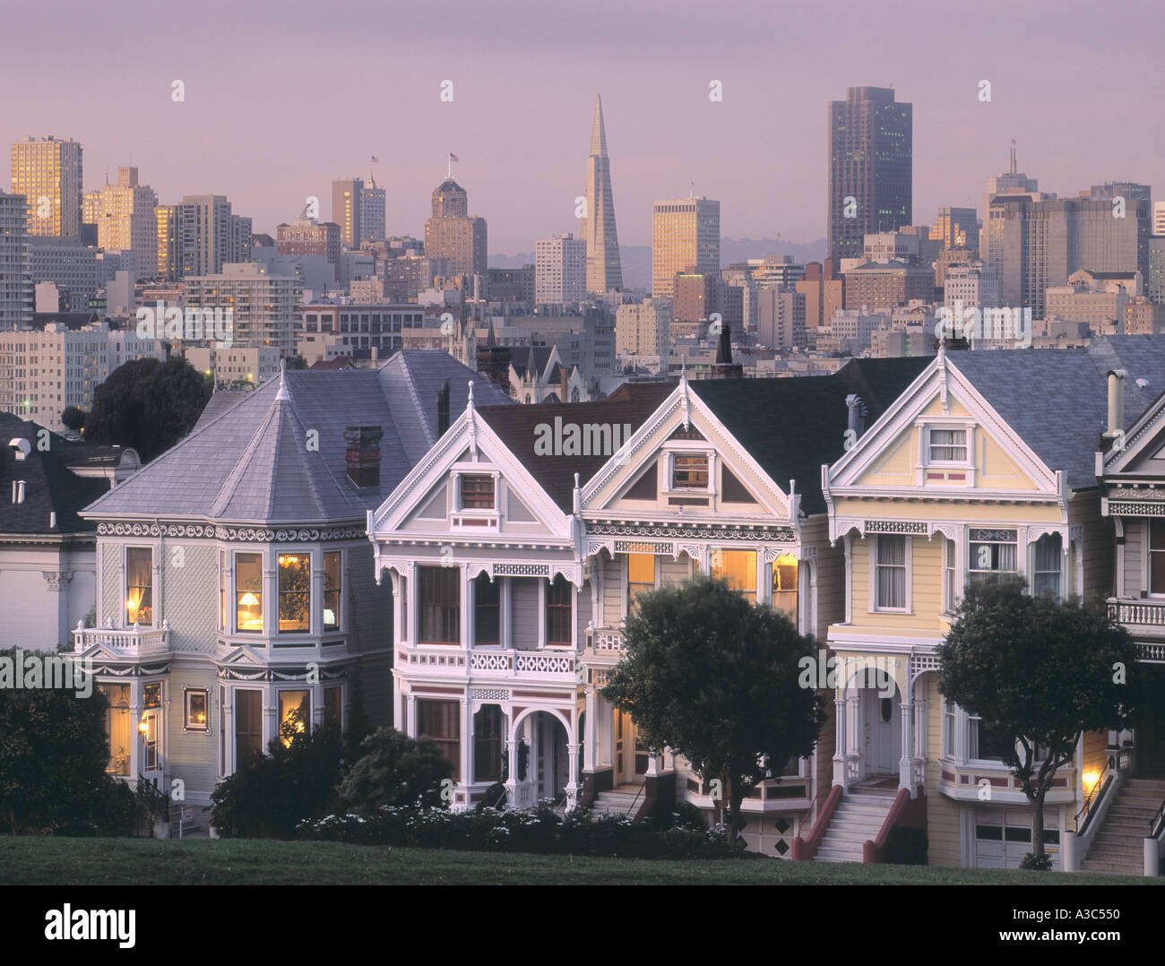 Case vittoriane su Steiner Street con TransAmerica Tower e la skyline di San Francisco al tramonto Foto Stock