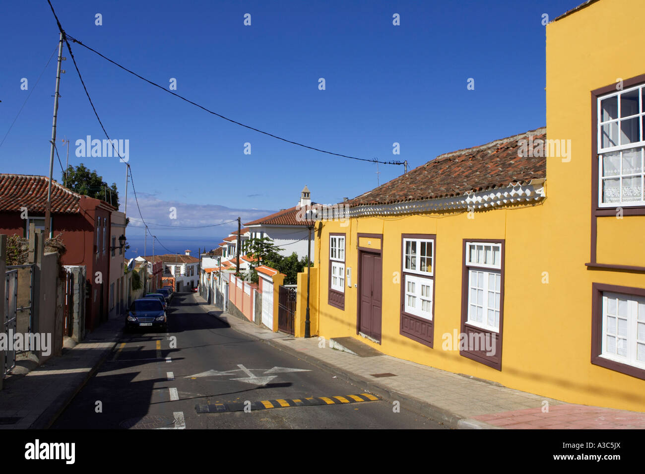 Strada stretta che conduce in basso verso il mare con colore giallo tradizionale edificio dipinto tacoronte Tenerife Isole Canarie Spagna Foto Stock