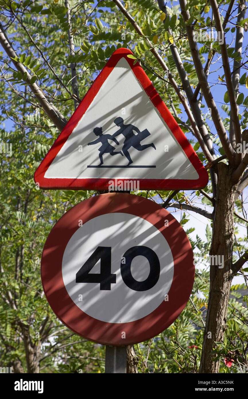 In stile europeo triangolare spia rossa di bambini e di attraversamento 40 km h round velocità segni di traffico in alberi Foto Stock