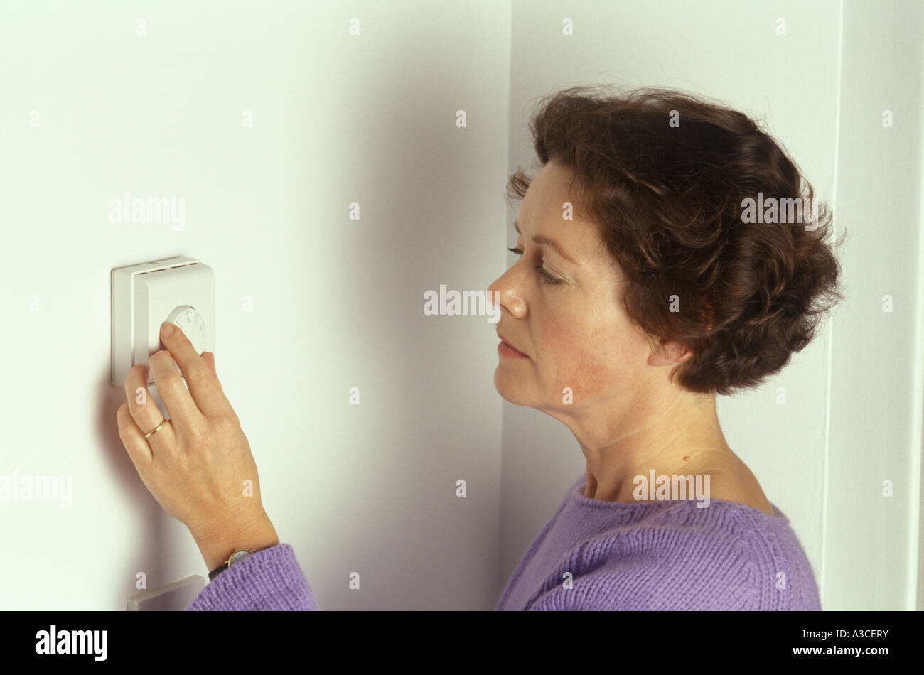 Donna ruotando verso il basso il termostato Foto Stock