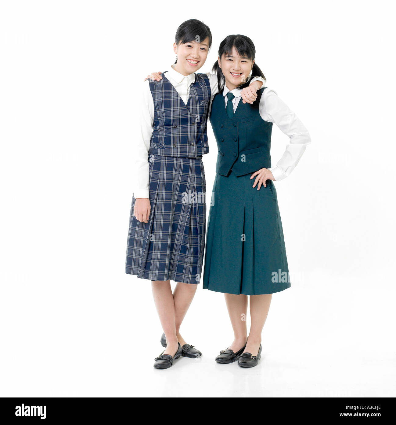 Due studenti di sesso femminile in diverse uniformi scolastiche mettere le loro braccia intorno reciprocamente le spalle Foto Stock