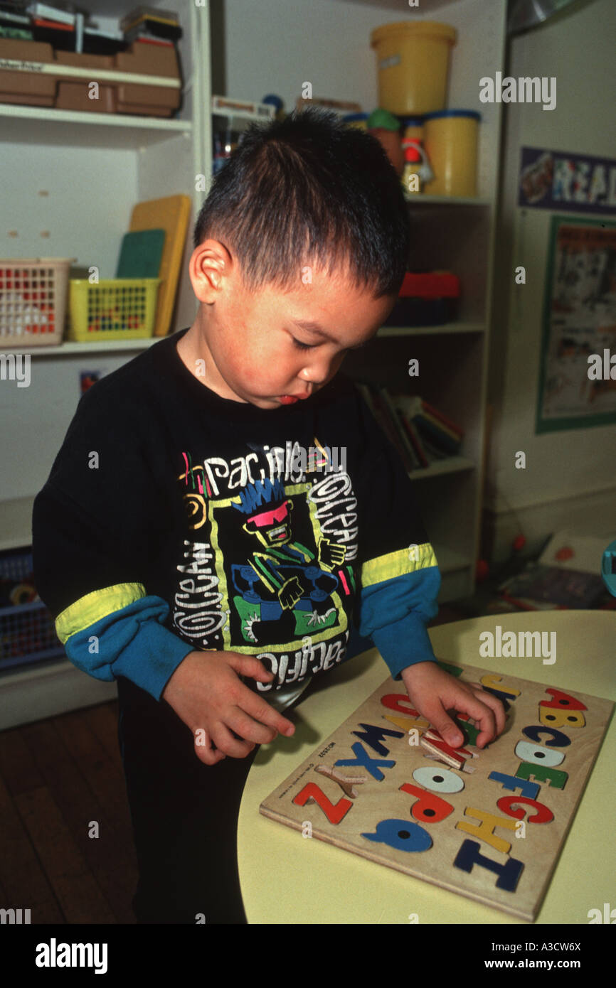 Chinese American boy gioca con lettera puzzle in una scuola materna a Brooklyn NY Foto Stock