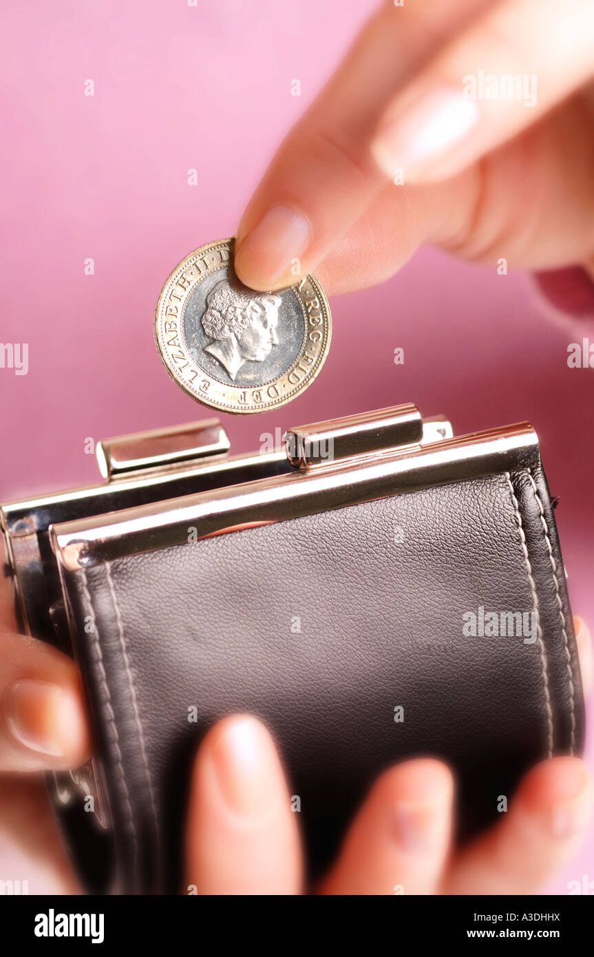 Donna mettendo due pound coin in borsa Foto Stock