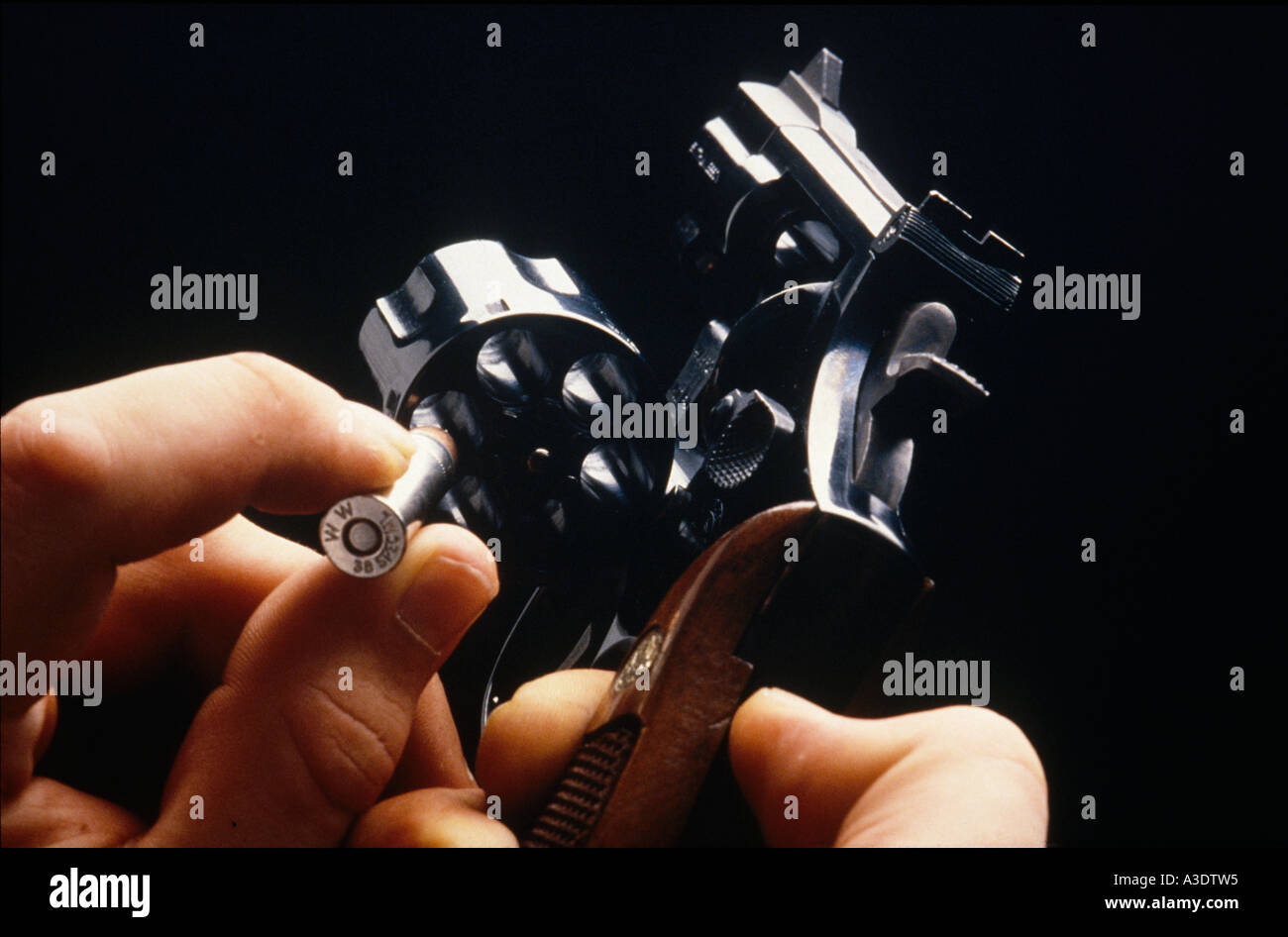Un uomo con le mani in mano tenendo un revolver, il caricamento di una cartuccia nella camera Foto Stock