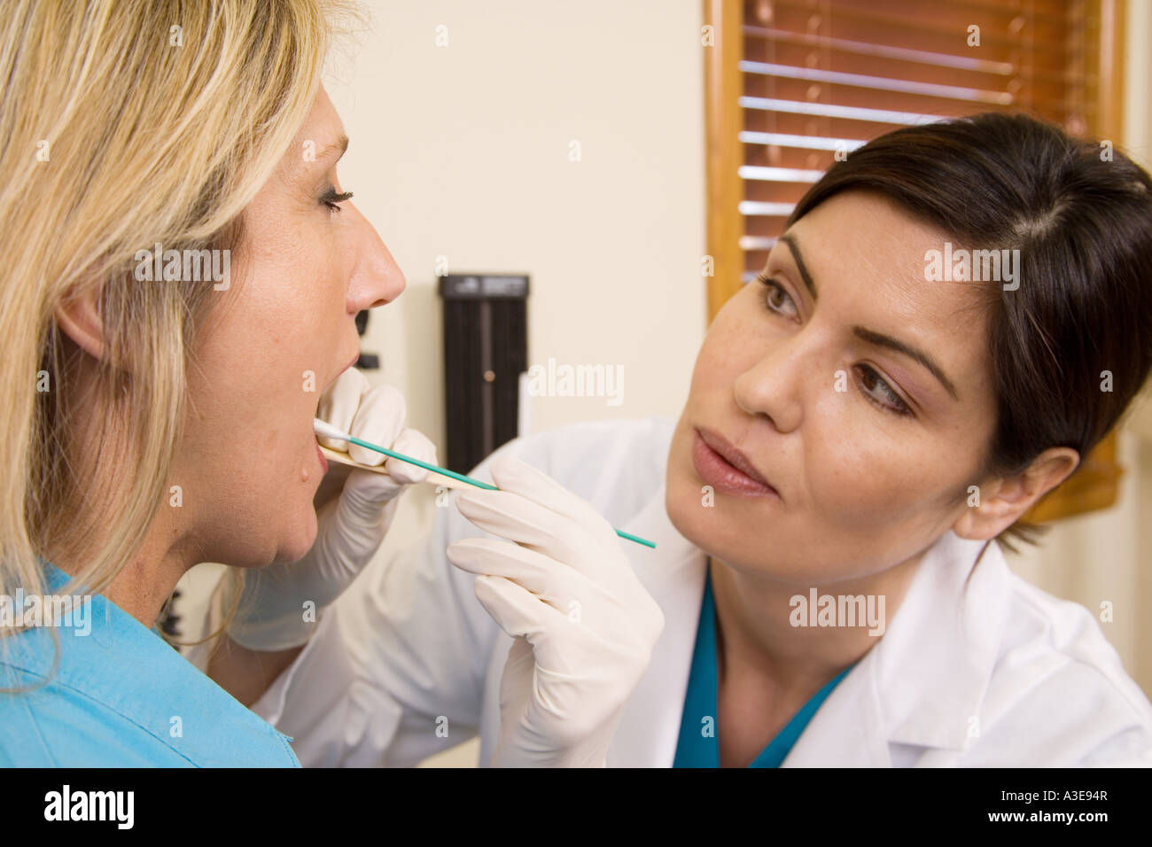 Medico o infermiere i tamponi la guancia di un paziente di sesso femminile per raccogliere cellule buccali per test del DNA o eventualmente strept gola cultura.. Foto Stock