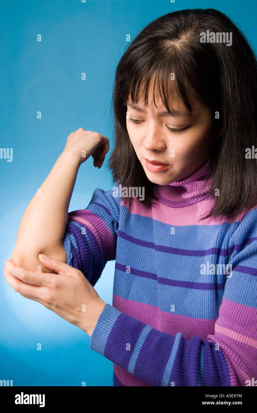 Donna asiatica con il gomito dolore. Foto Stock