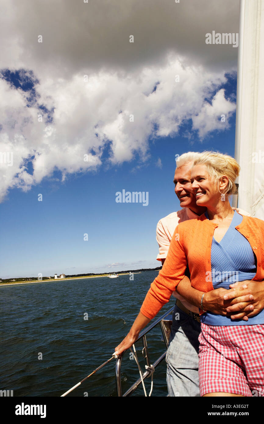 Uomo maturo abbracciando una donna matura da dietro in una barca a vela e sorridente Foto Stock