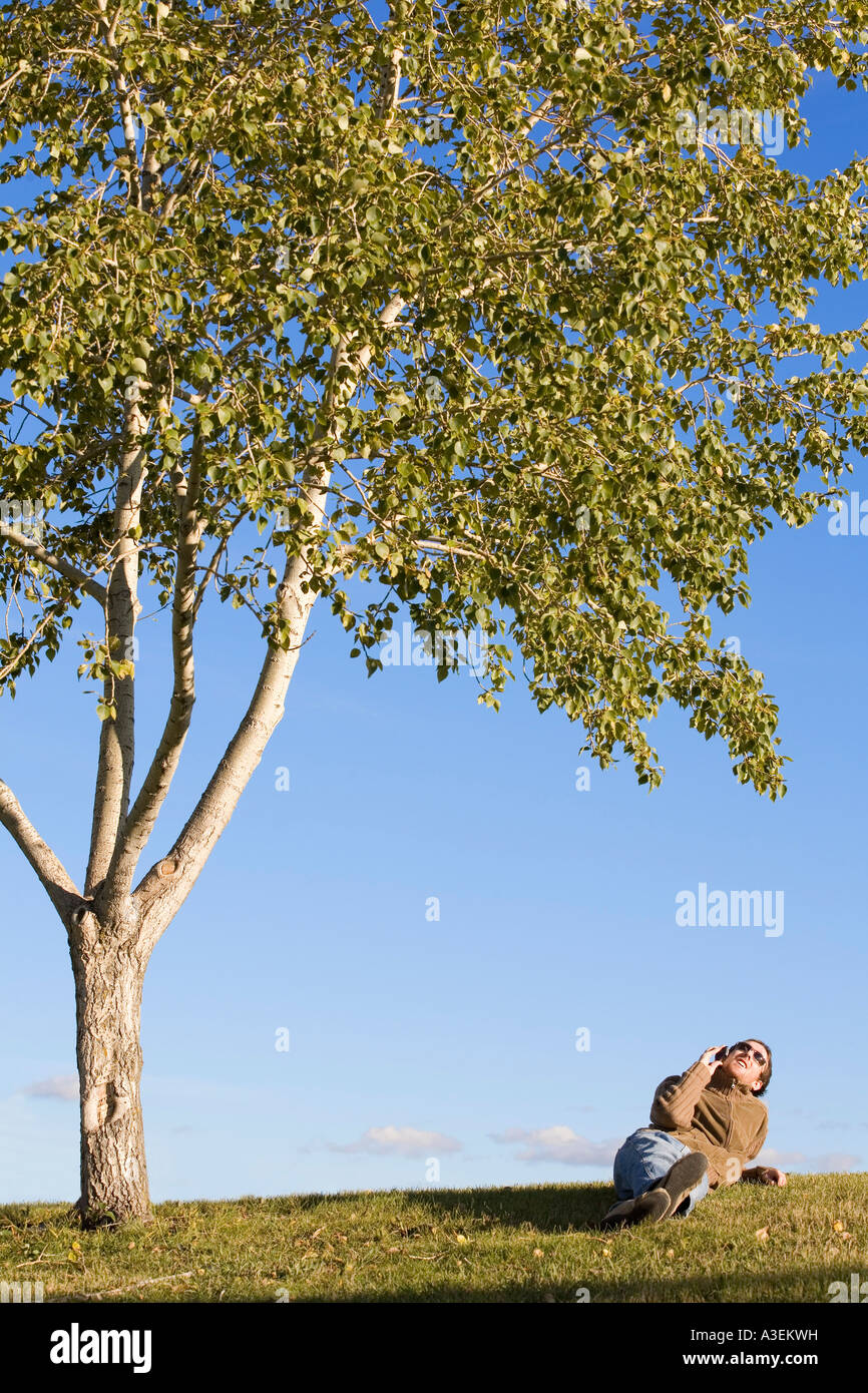 Uomo appoggiato sotto agli alberi Foto Stock