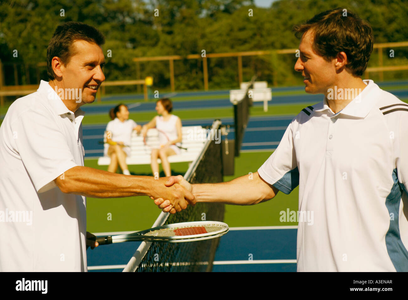 Profilo laterale di un uomo maturo si stringono la mano con una metà uomo adulto su un campo da tennis Foto Stock