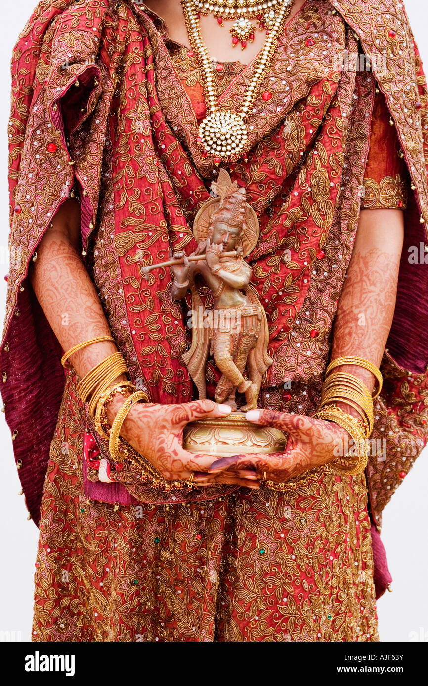 Metà vista in sezione di una sposa tenendo un idolo di Krishna Foto Stock