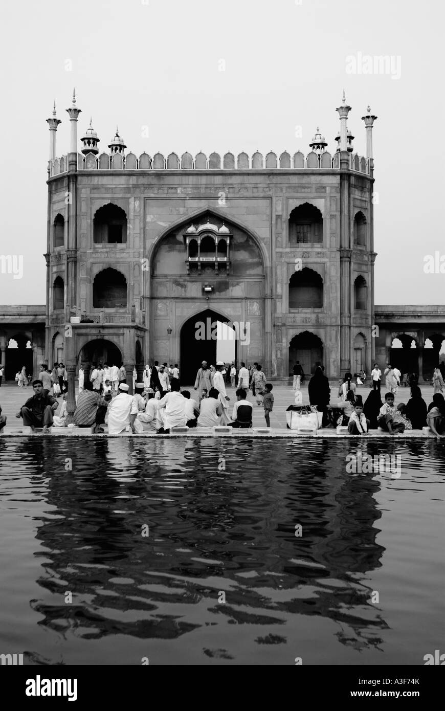 Vista posteriore di un gruppo di persone sedute al di fuori di una moschea Jama Masjid, New Delhi, India Foto Stock