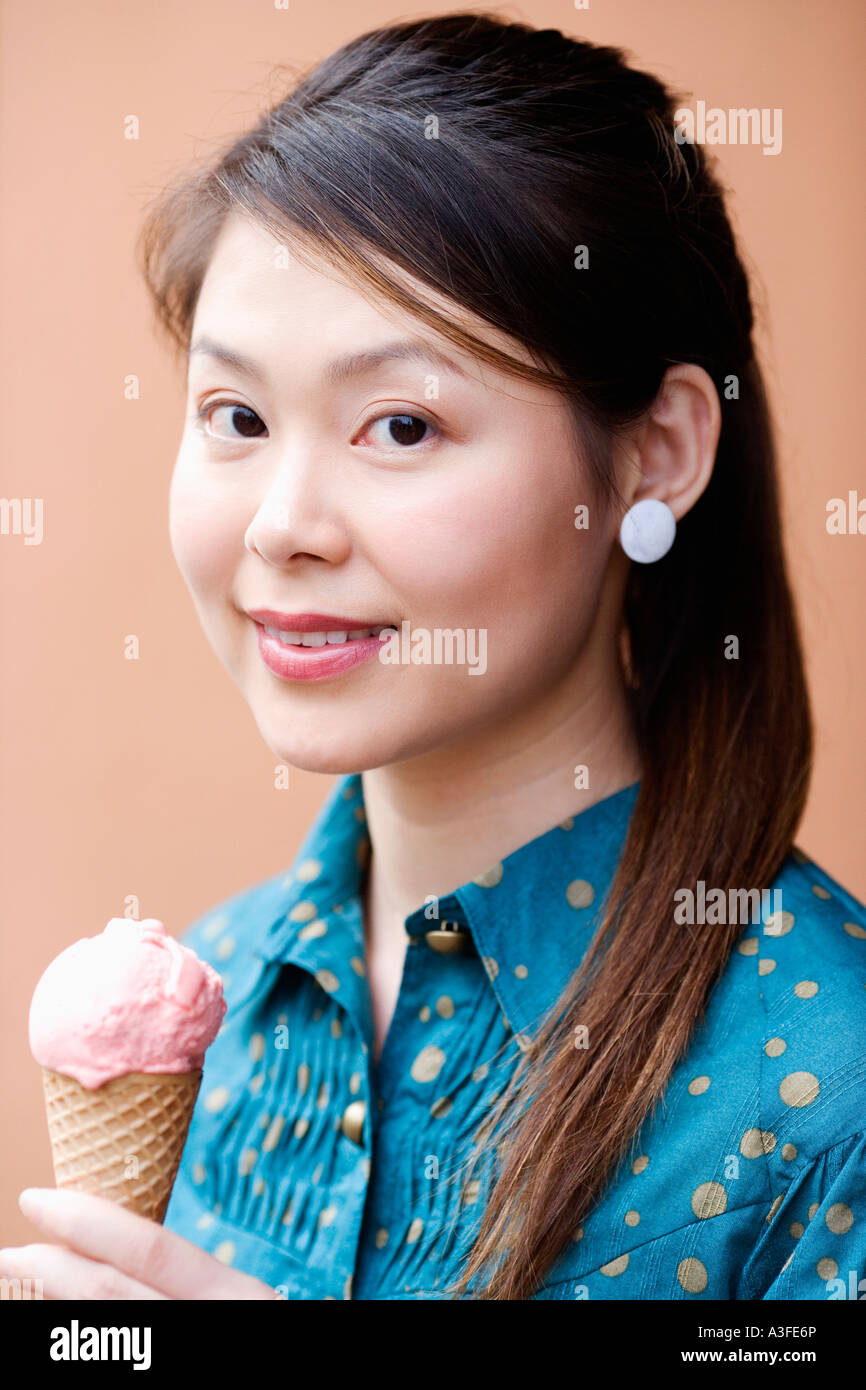 Ritratto di una giovane donna di trattenimento di un cono gelato Foto Stock