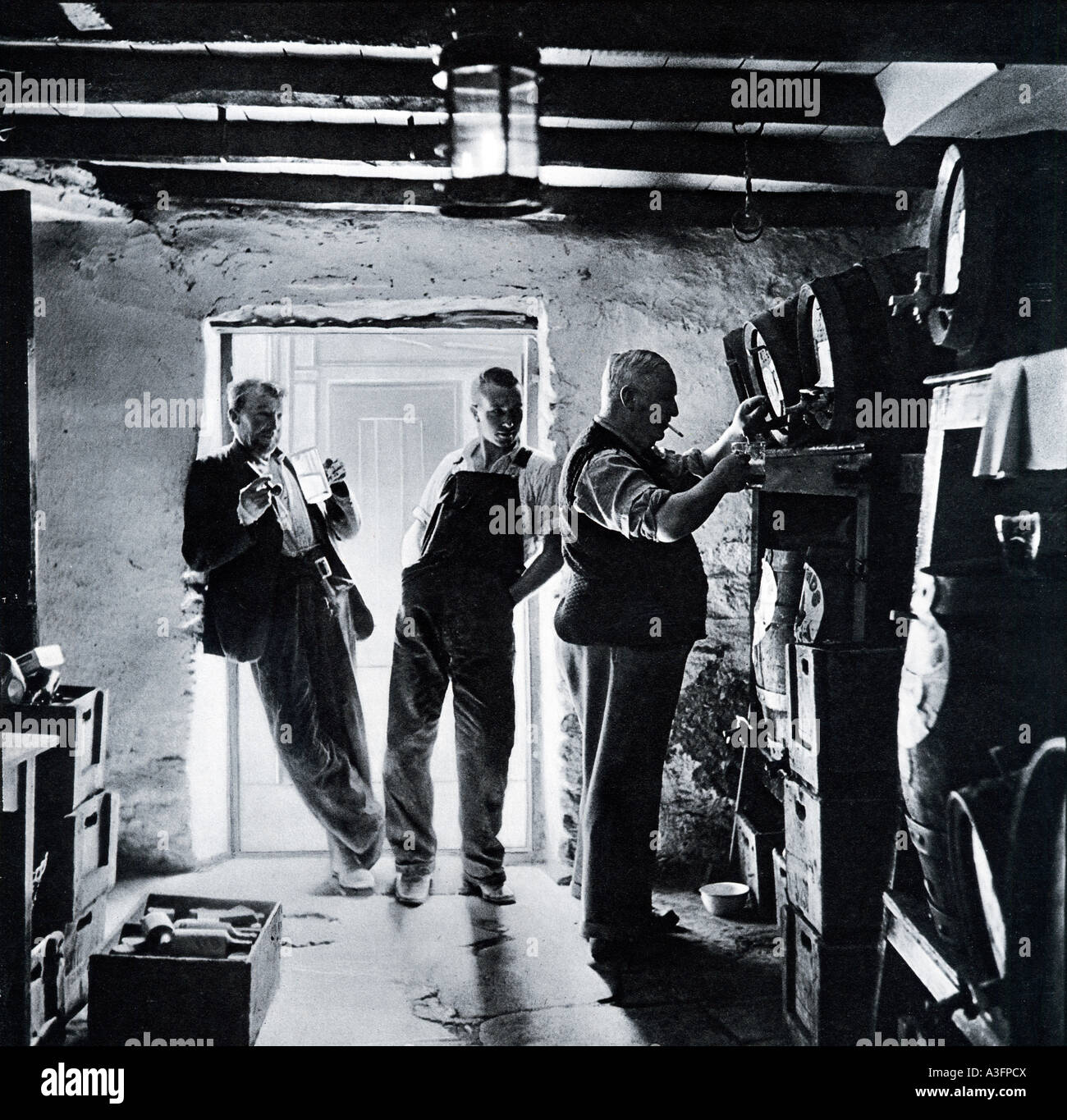 Uno dalla botte 1930 foto di un pub il locatore il disegno di una pinta di birra direttamente da una canna in cantina Foto Stock