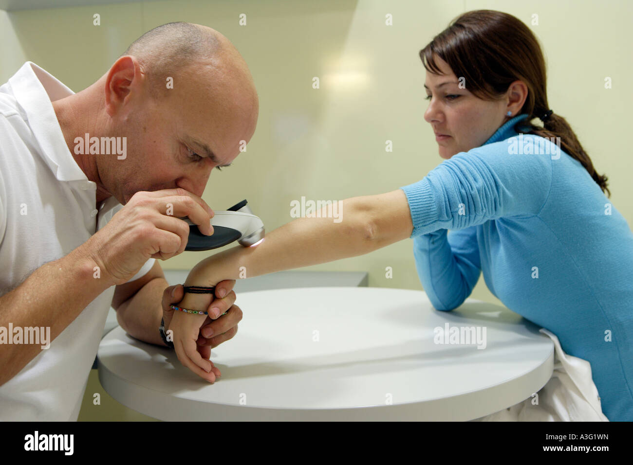 Il specialista di pelle MD Serko von Schmiedeberg esamina un paziente con un dermatoscope Foto Stock