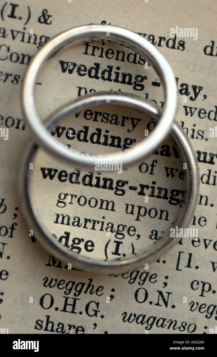 Gli anelli di nozze su un dizionario che mostra la parola matrimonio e anello di nozze Foto Stock