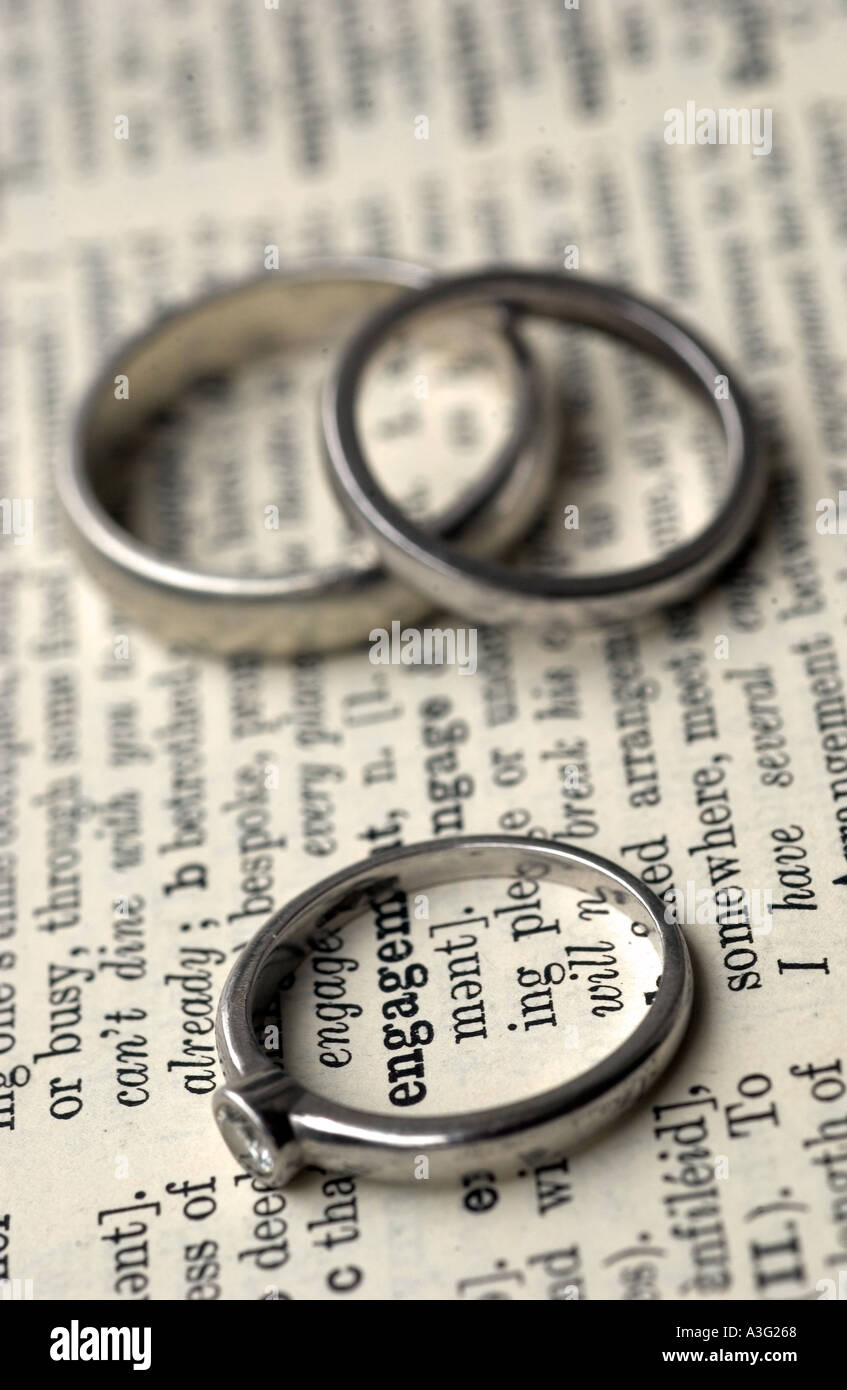 Impegno e gli anelli di nozze su un dizionario che mostra la parola engage Foto Stock