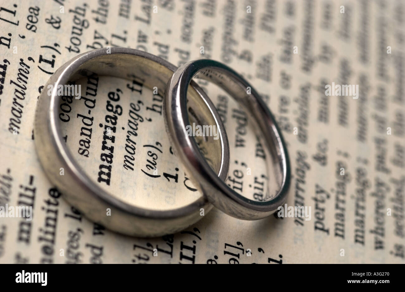 Gli anelli di nozze su un dizionario che mostra la parola matrimonio Foto Stock