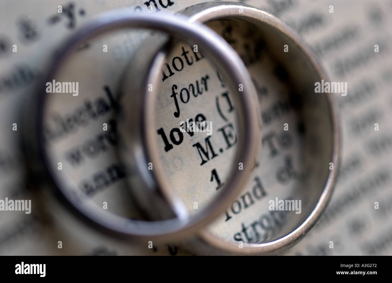 Gli anelli di nozze su un dizionario che mostra la parola amore Foto Stock