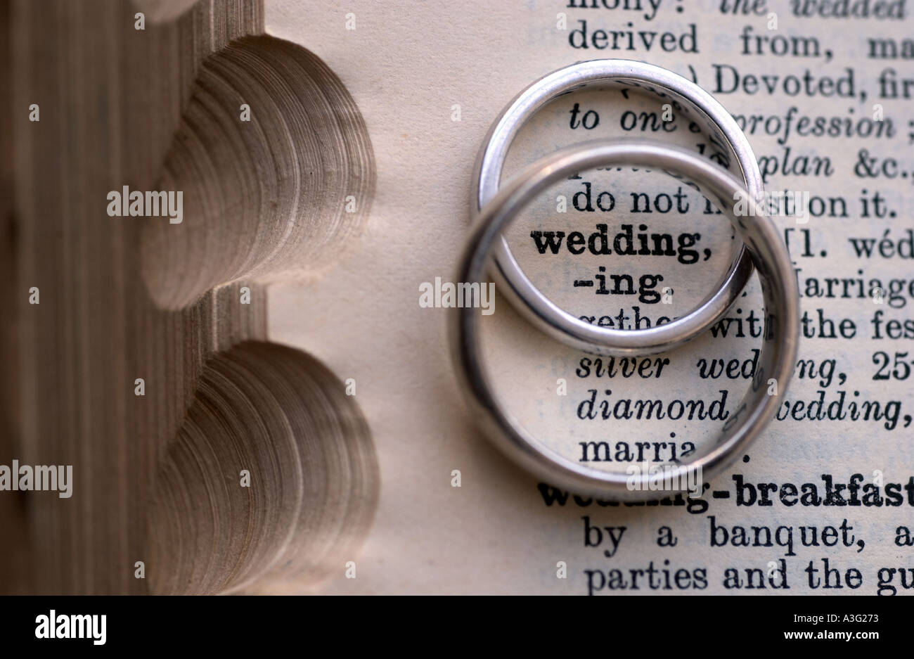 Gli anelli di nozze su un dizionario che mostra la parola matrimonio Foto Stock