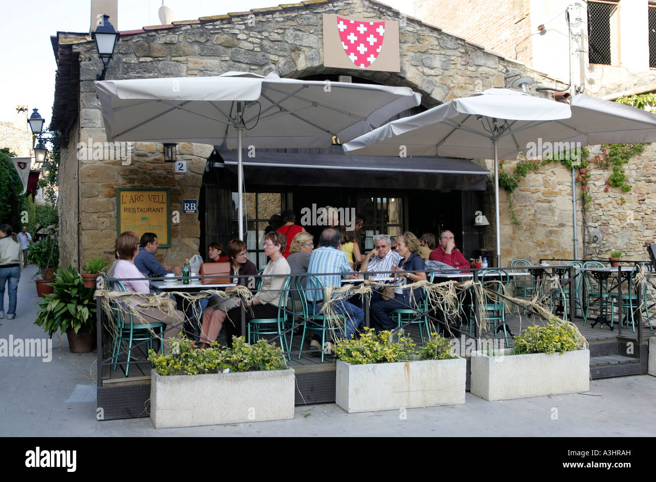 I turisti seduti su una terrazza ristorante nel borgo medievale di Peratallada in Catalogna, Spagna Foto Stock