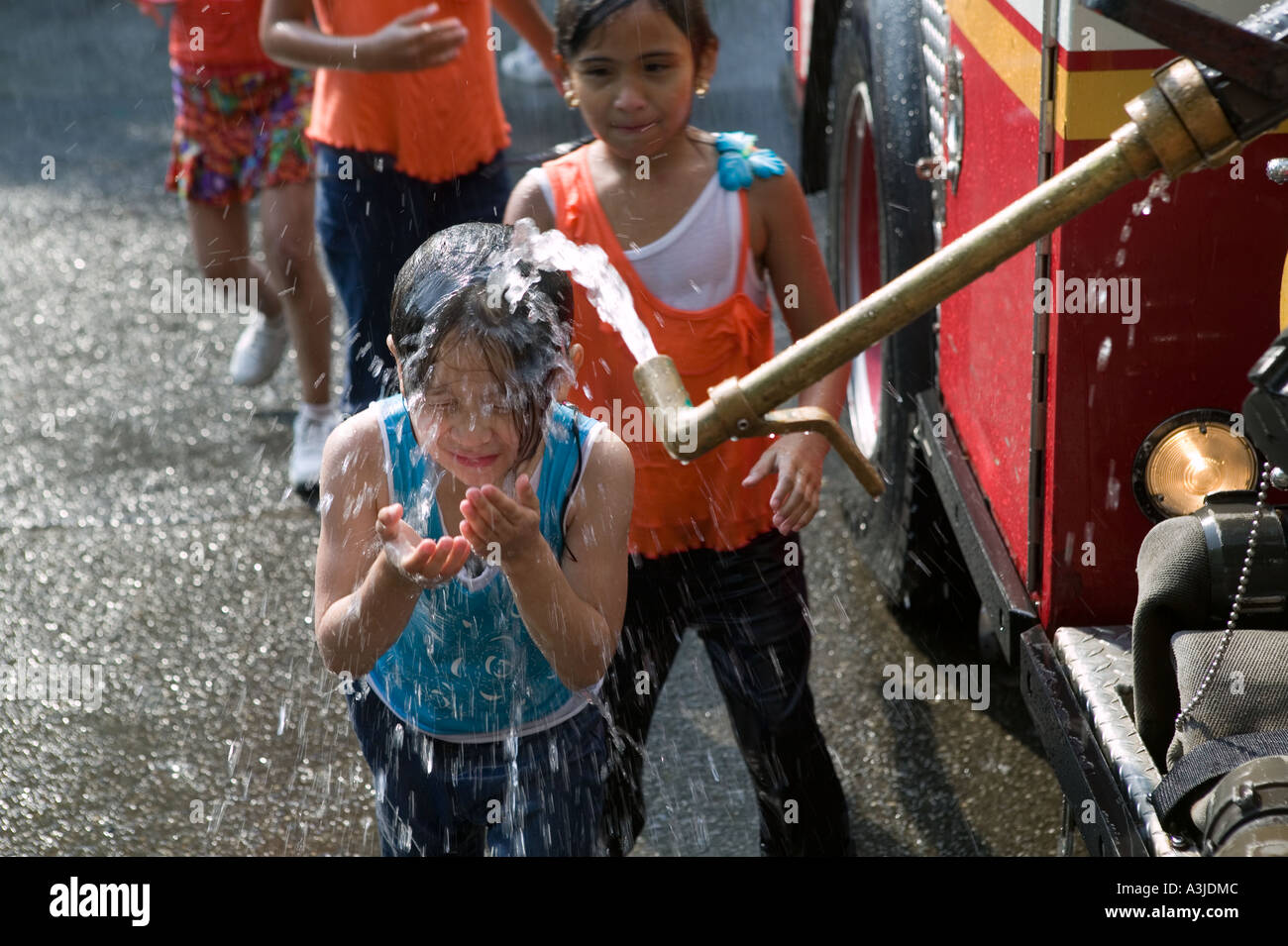Bambini raffreddare sotto un camion dei pompieri s usa il tubo flessibile in una calda giornata estiva Giugno 2005 Foto Stock