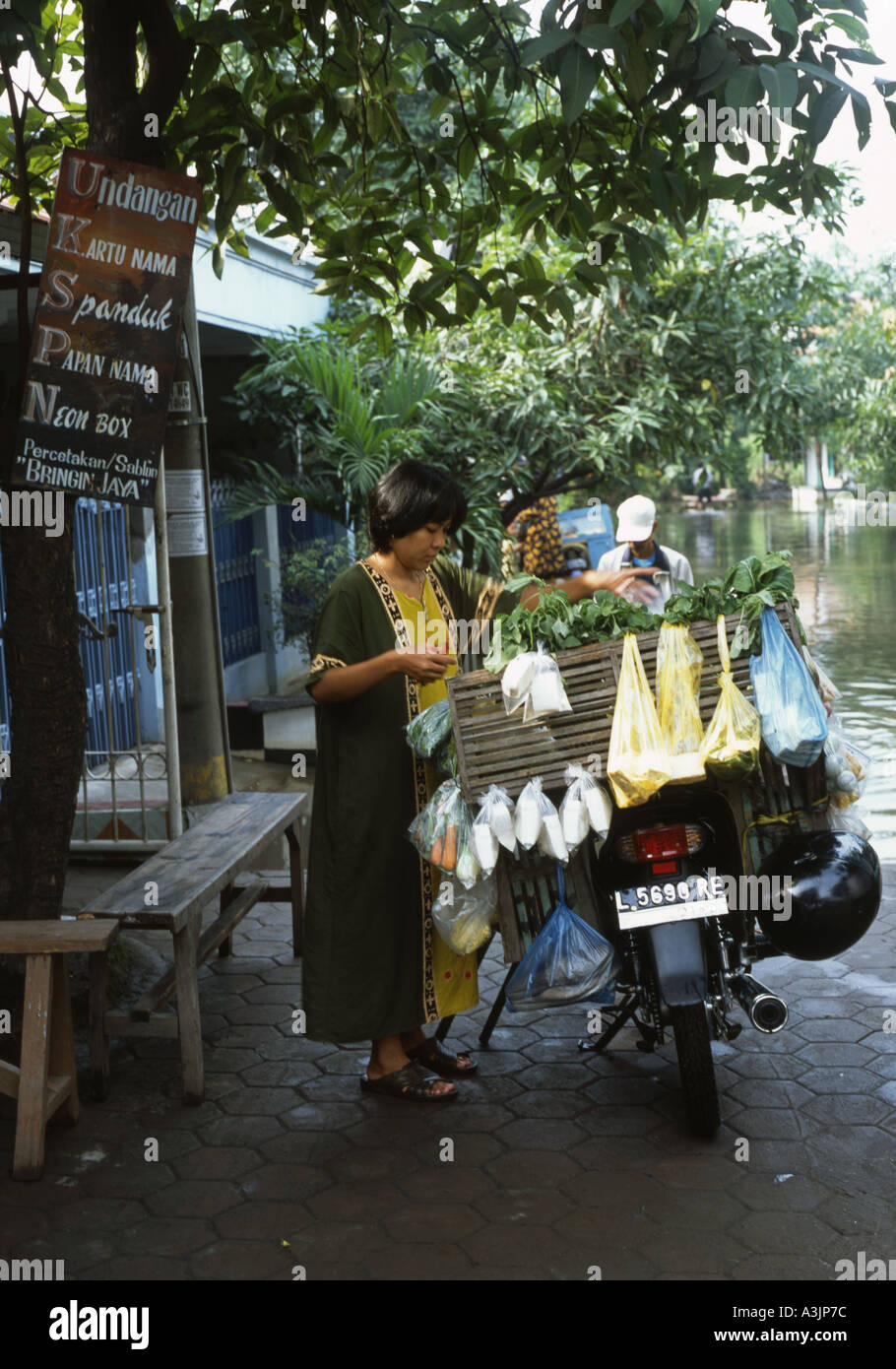 Donna locale prepara il suo cibo carrello nelle strade inondate di trosobo vicino a Surabaya indonesia java Foto Stock