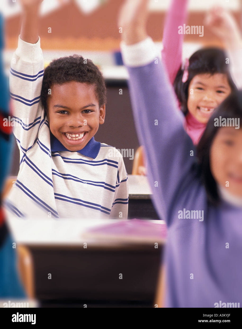 African American Asian Latino studenti alzando le mani nella scuola elementare classroom Foto Stock