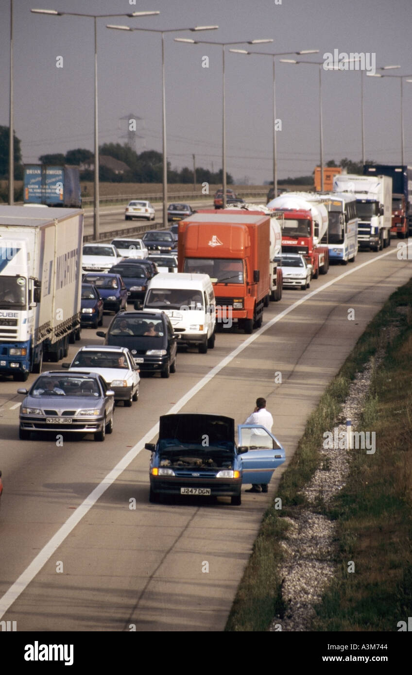 Vista aerea lunga coda di M25 autostrada camion camion furgone traffico bloccato in jam con conducente accanto a auto rotta su spalla dura Inghilterra UK Foto Stock