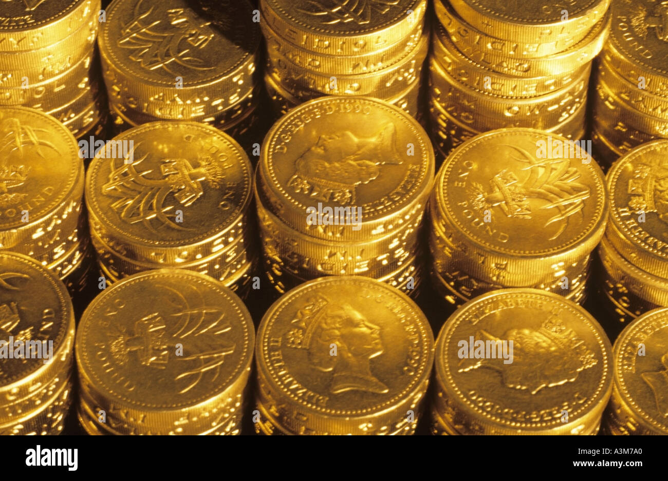 Close up di pile di denaro del Regno Unito una sterlina monete in contanti sotto illuminazione oro Concetto di immagine per nido uovo pila di risparmio di denaro di pile di denaro Foto Stock