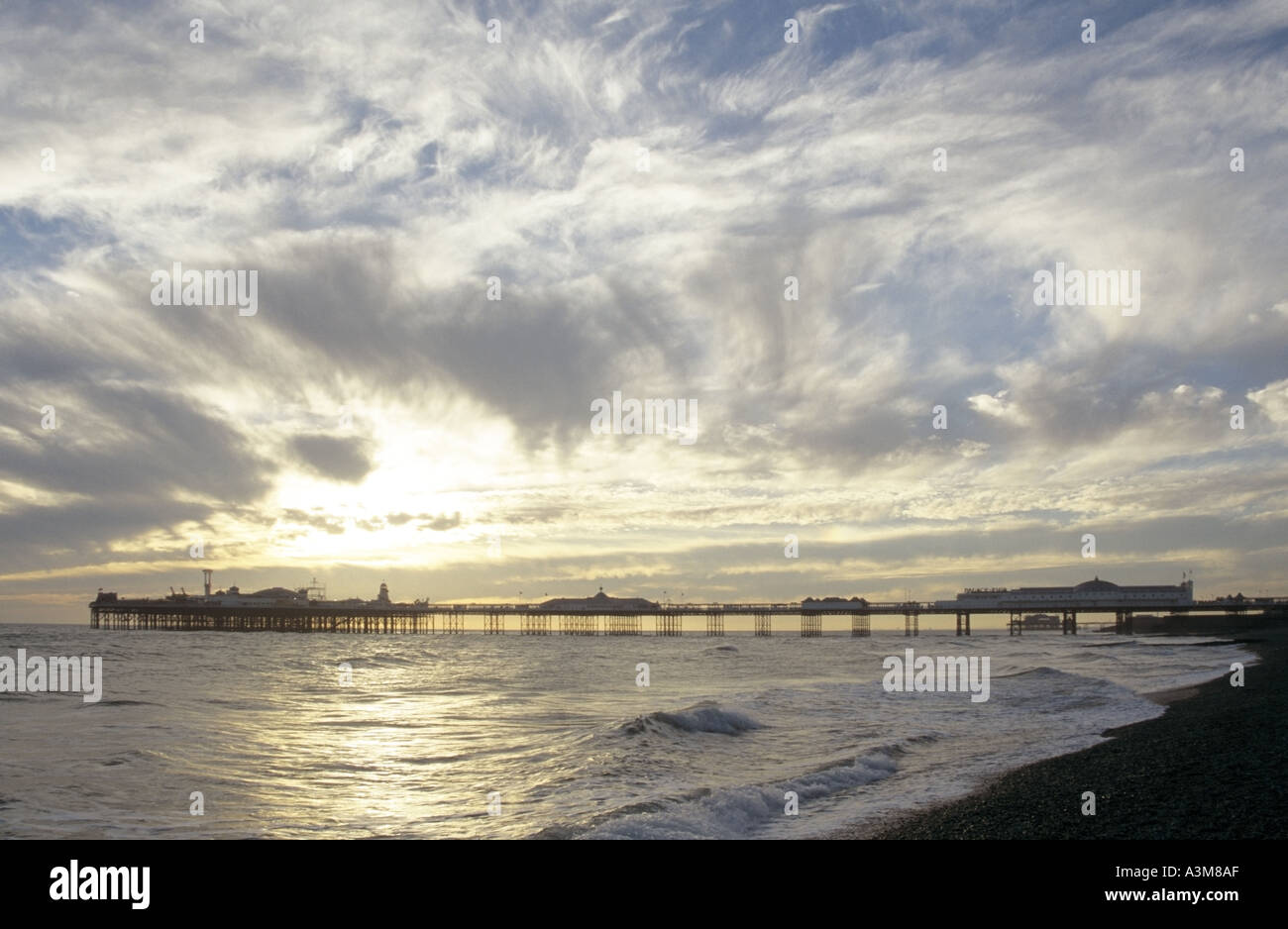 East Sussex costa a Brighton Pier parco di divertimenti al tramonto cielo tempestoso e tempo sopra la costa della località balneare con spiaggia di ciottoli costa Inghilterra UK Foto Stock