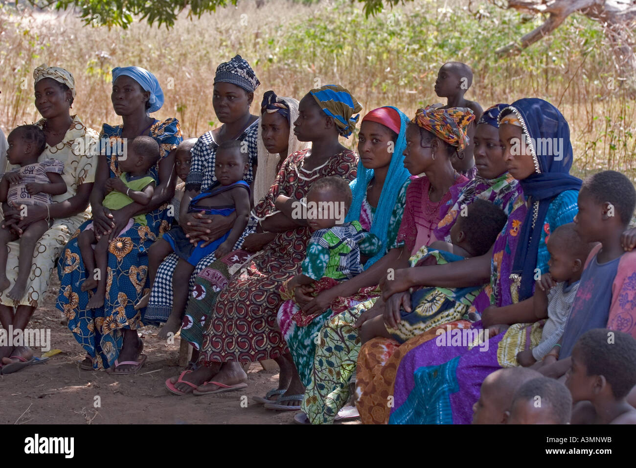 Un gruppo di giovani madri con i loro bambini alla riunione del villaggio nel nord del Ghana Foto Stock