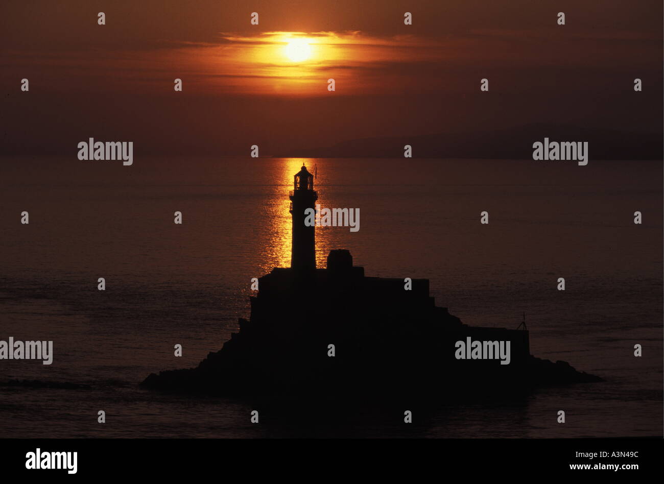 Fastnet rock e il faro al tramonto sul mare calmo Foto Stock Fastnet rock e il faro al tramonto sul mare calmo Foto Stock