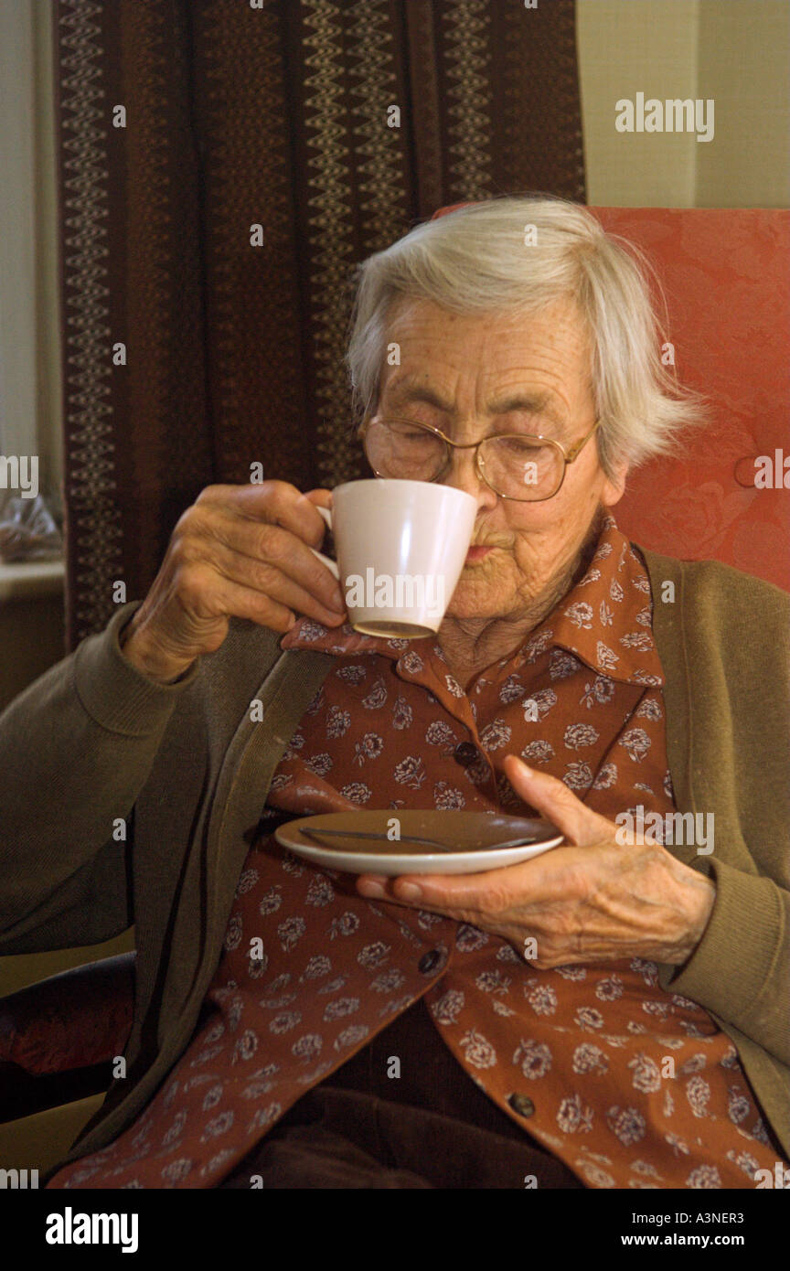 Donna anziana sorseggiando una tazza di tè Foto Stock