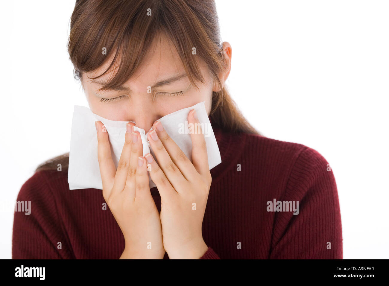 Una giovane donna soffia il naso sul tessuto Foto Stock