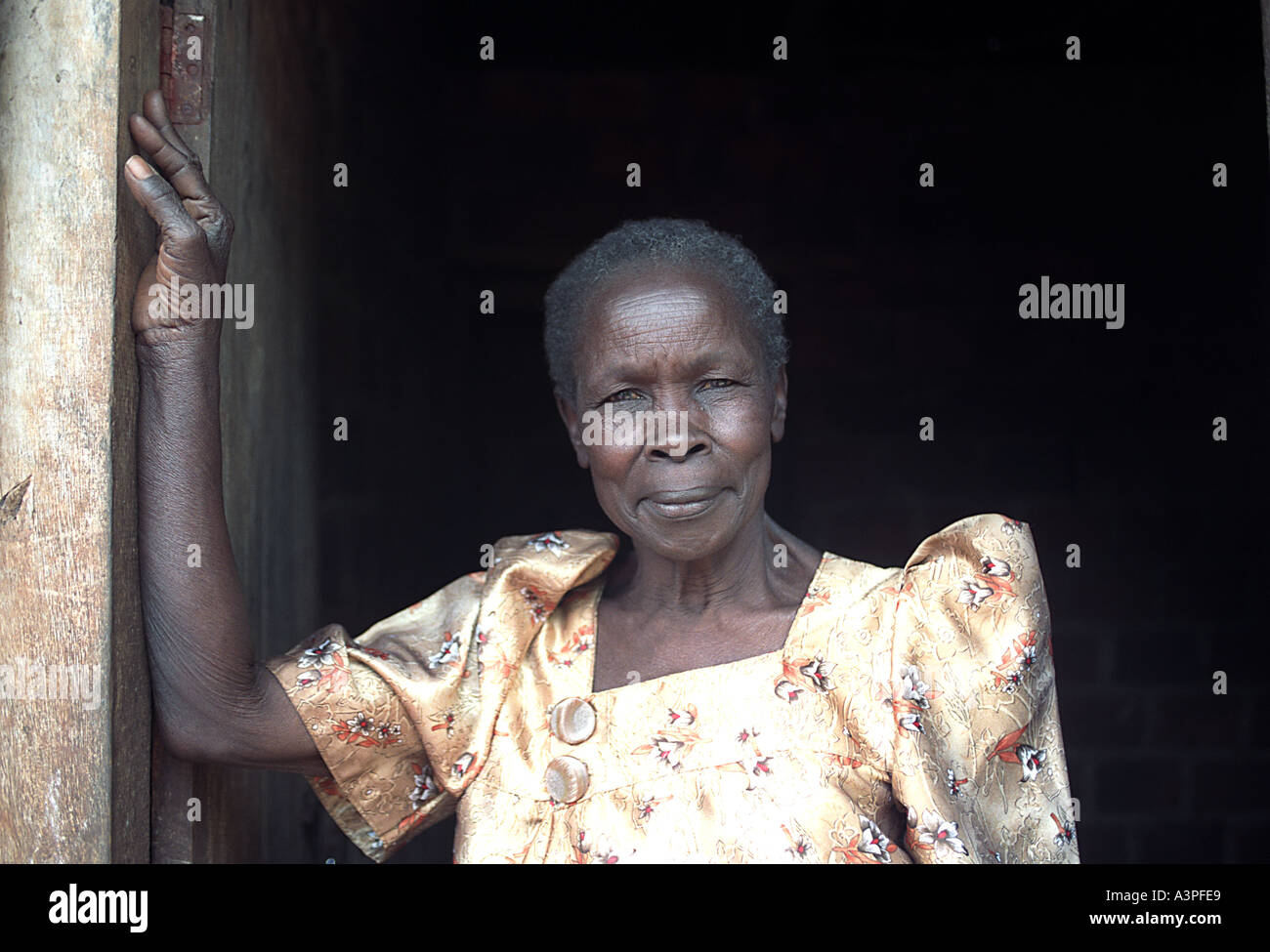 Ritratto di nonna in Uganda nel vano della porta della sua casa Foto Stock