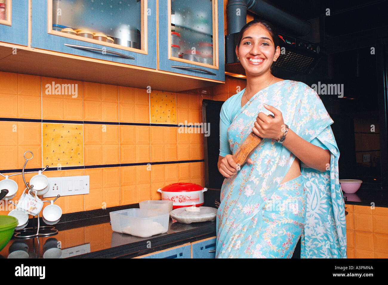 RHS99524 South Asian donna indiana che lavora in cucina con sorriso rendendo chapatti pane indiano guardando verso di voi MR 522 Foto Stock
