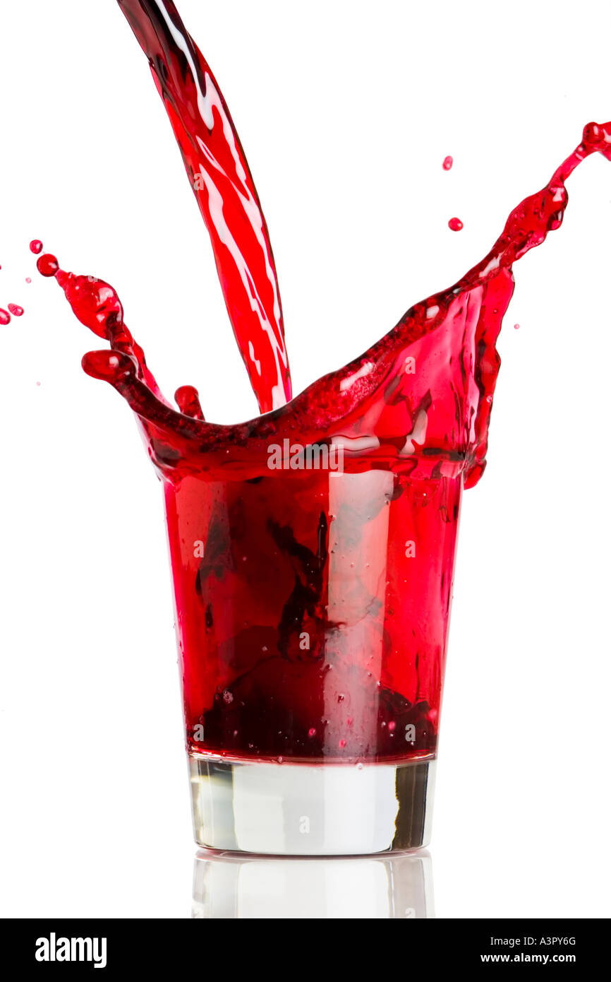 Un rosso liquido viene versato in, e spruzzi su un vetro. Foto Stock