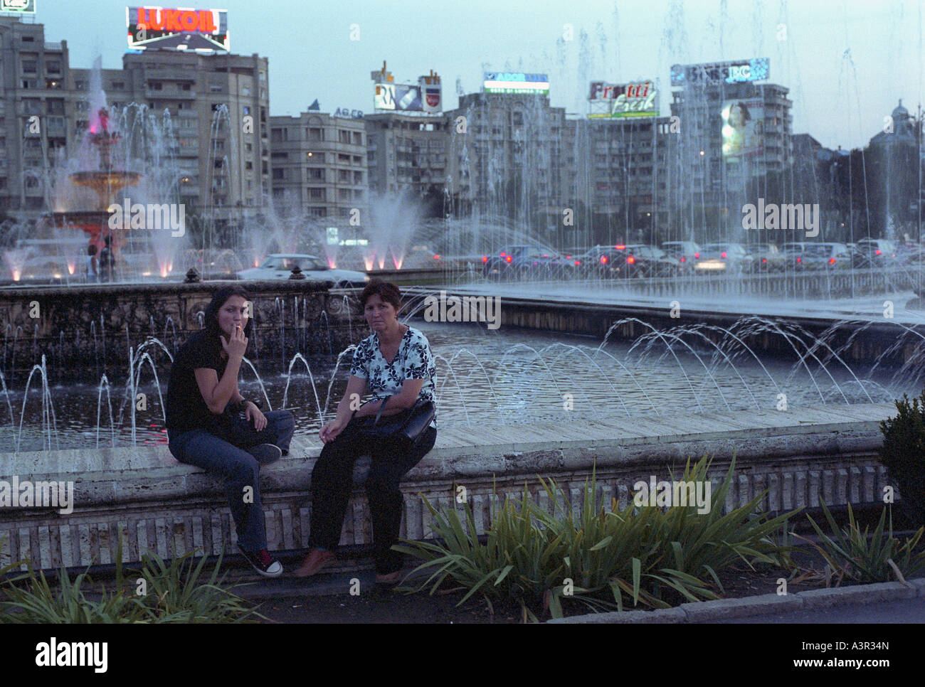 Due donne seduti ad una fontana in un parco alla unità quadrata (Piata Unirii), Bucarest, Romania Foto Stock