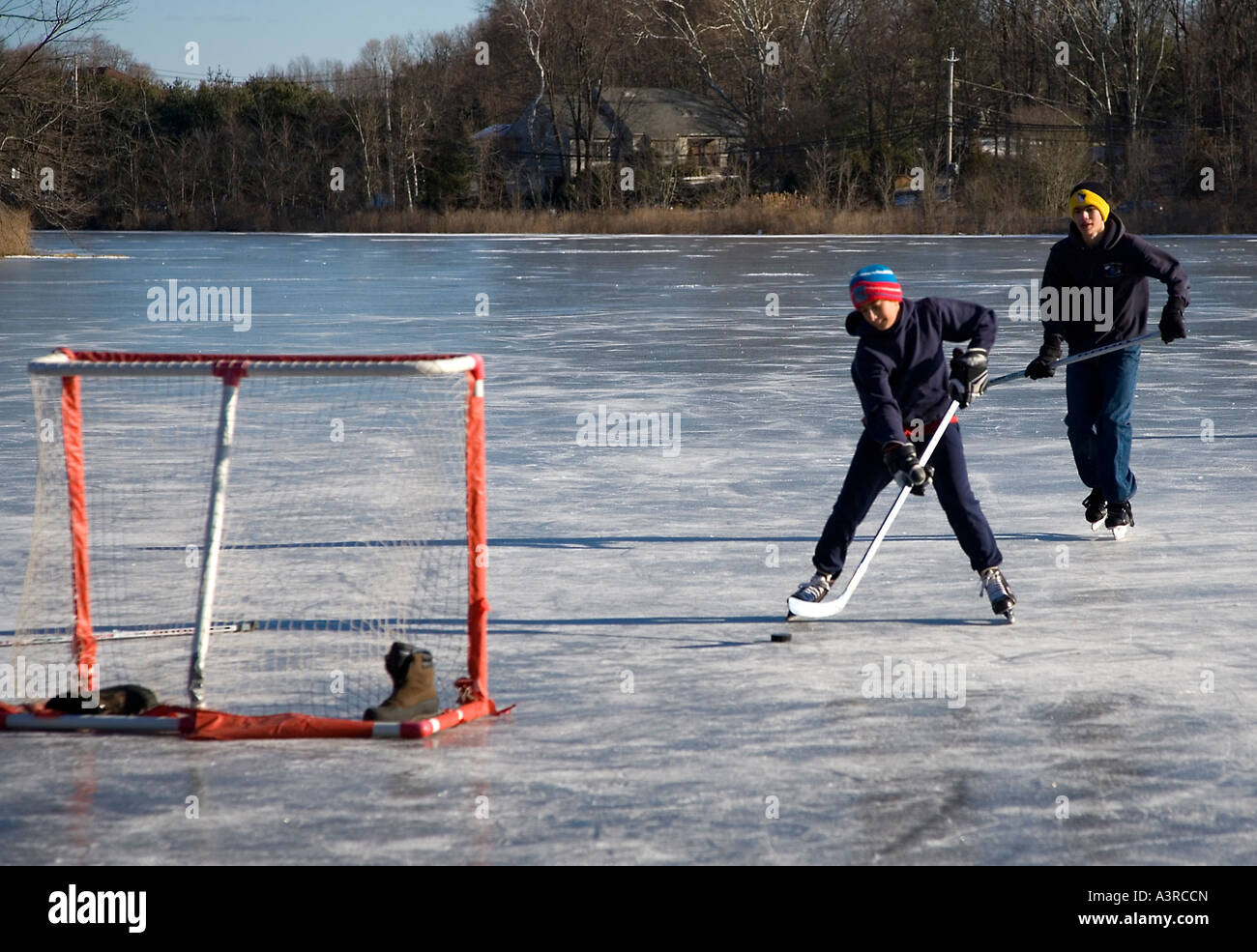Due ragazzi giocare hockey su ghiaccio su un laghetto congelato Foto Stock