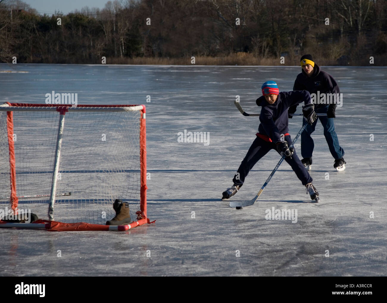 Ragazzi che giocano a hockey su un laghetto ghiacciato Foto Stock