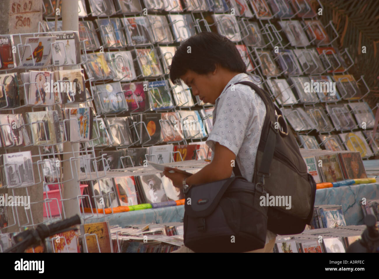 Persona in cerca di copie illegali di CD e DVD, Bangkok, Thailandia Foto Stock