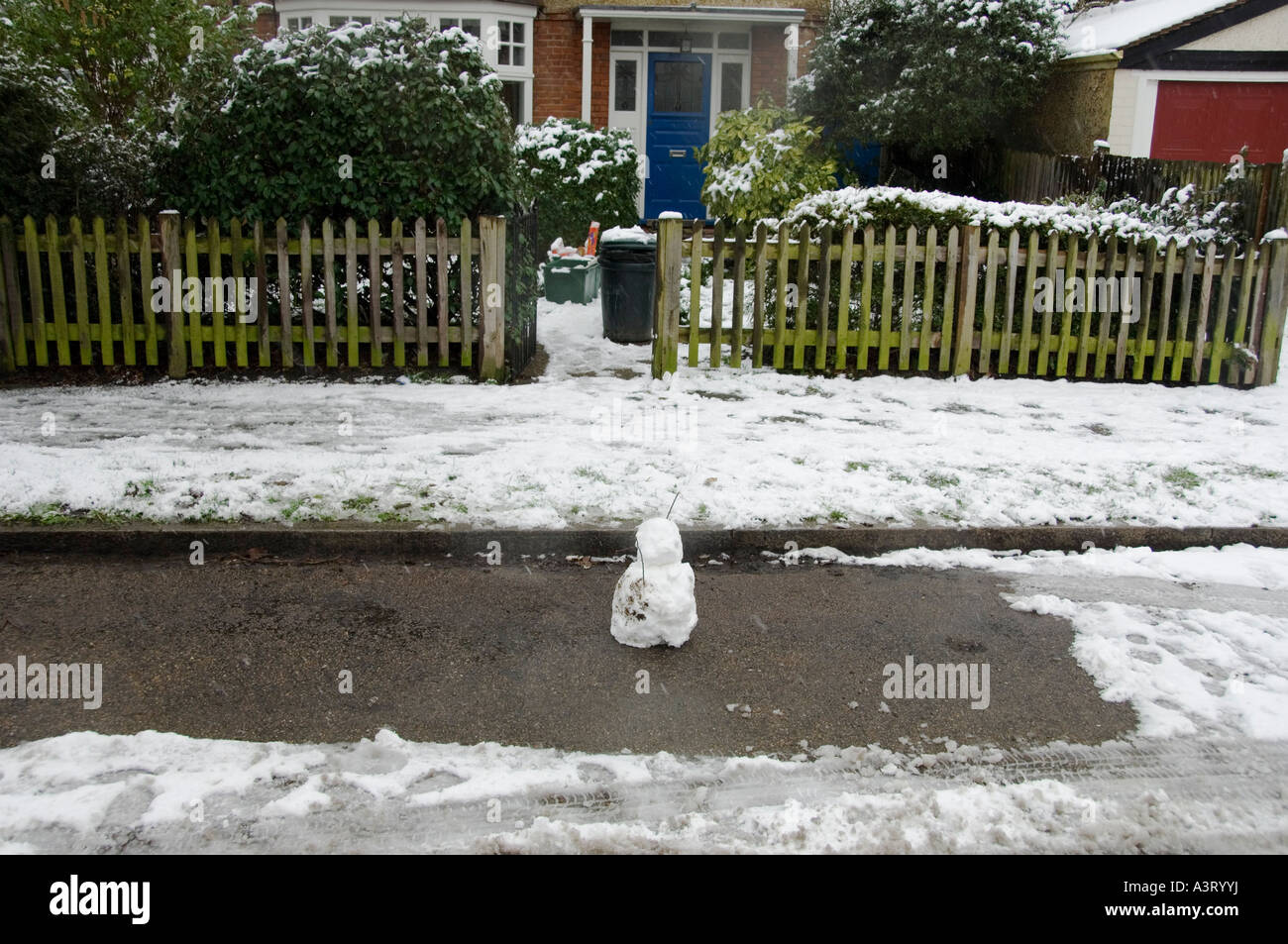 Piccolo pupazzo di neve su uno spazio vuoto parcheggio al di fuori di una casa suburbana a Londra, Inghilterra Foto Stock